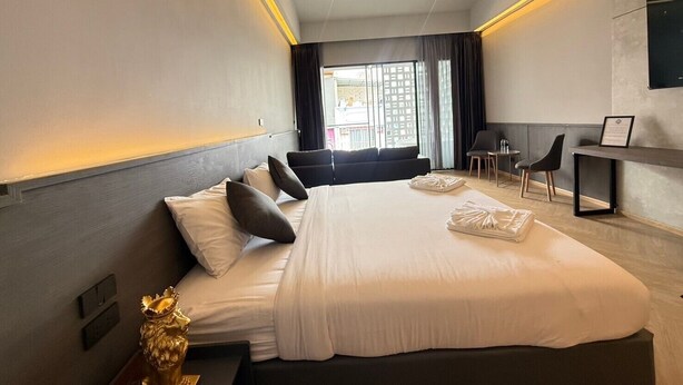 A modern hotel room with a large bed, bedside tables, a desk, and a chair. - Leon's Loft House (Patong)