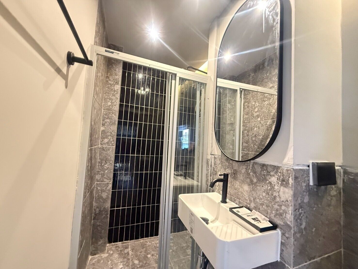 A modern bathroom with a glass shower enclosure, a white sink, and a large mirror.