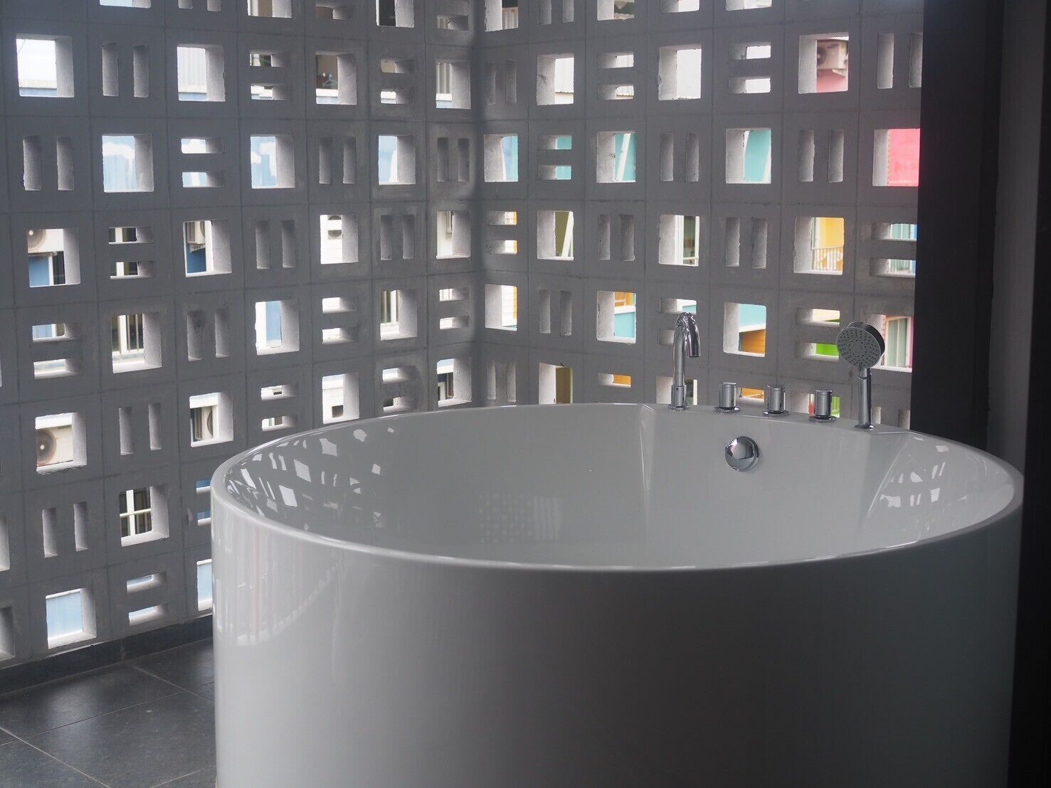 A modern bathroom with a large freestanding bathtub, a wall-mounted sink, and a showerhead.