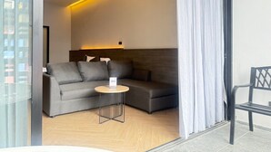 A modern room with a grey sofa, a small round table, and a bed with a headboard. - Leon's Loft House (Patong)