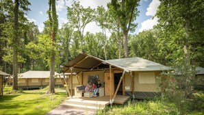 A campsite with a single tent featuring a porch and a small deck. - Luxuszelt im Serengeti Park (Hodenhagen)