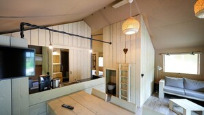 A compact living space with a kitchenette, a dining area, and a seating area with a sofa and a table. - Luxuszelt im Serengeti Park (Hodenhagen)