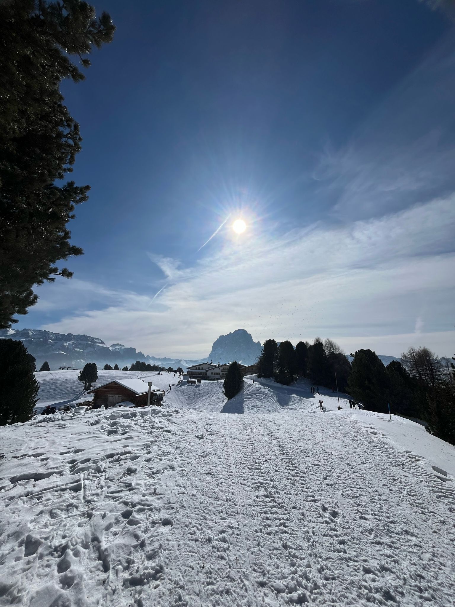 A snowy landscape with a clear sky, a prominent mountain in the background, and a few buildings.