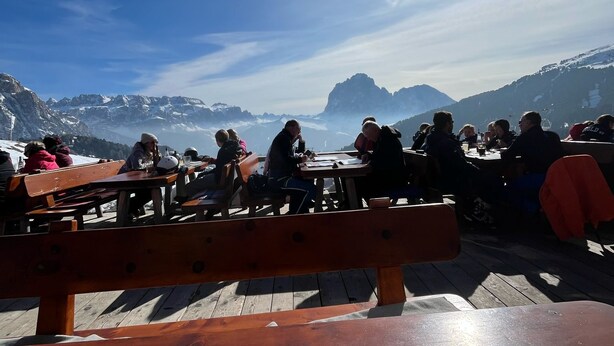 Une terrasse en bois avec des bancs, offrant une vue sur un paysage montagneux.