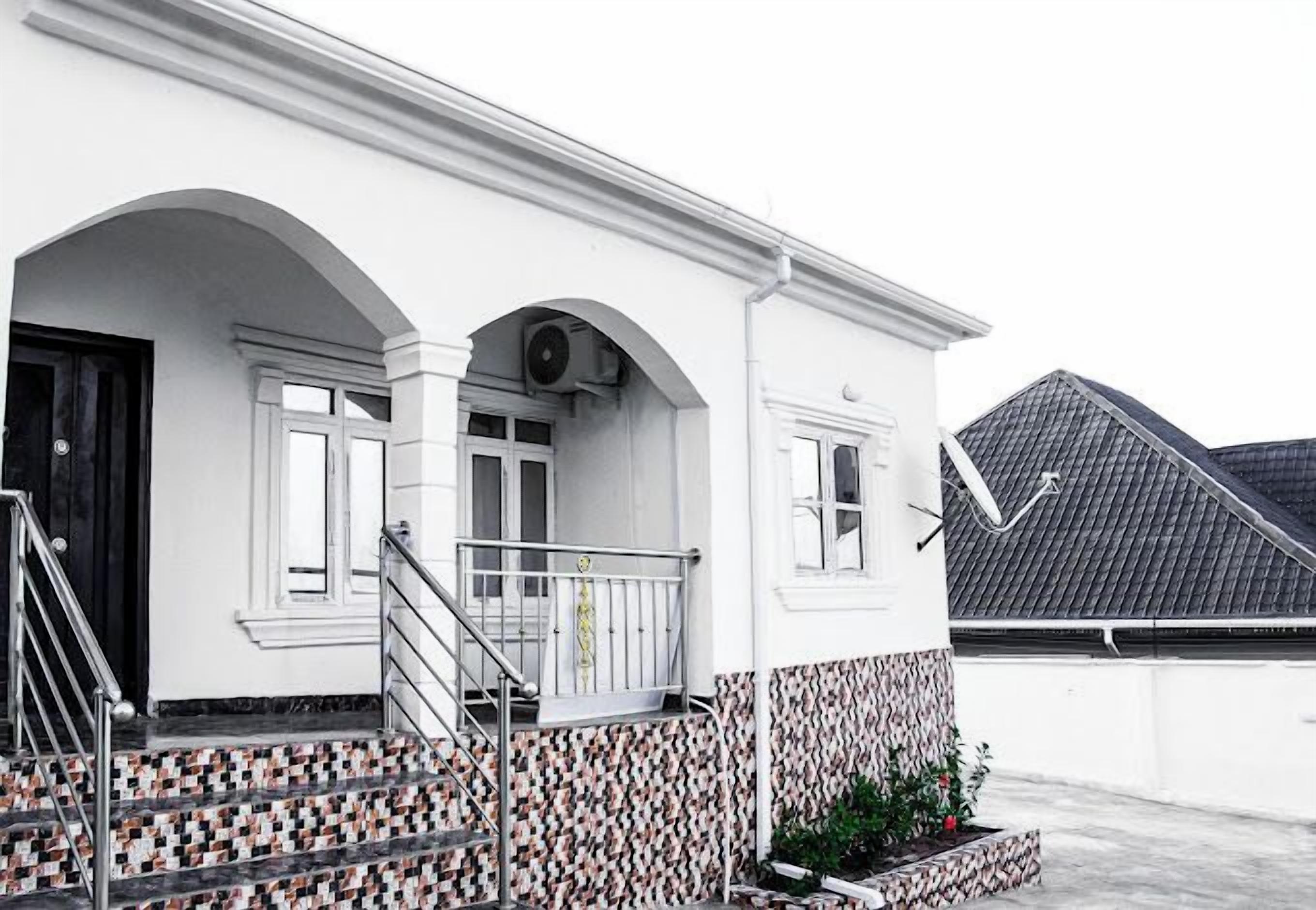 Un bâtiment blanc avec une entrée carrelée, un balcon et un escalier.