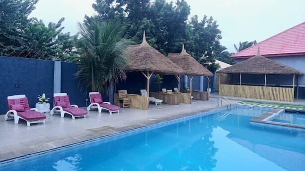 A swimming pool with lounge chairs and thatched-roof structures. - FFA RESORT CENTRE (Akure)