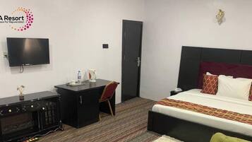 Een hotelkamer met een bed, een bureau, een televisie, een stoel en een koffer.