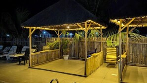 A covered outdoor seating area with wooden furniture and a thatched roof structure. - FFA RESORT CENTRE (Akure)