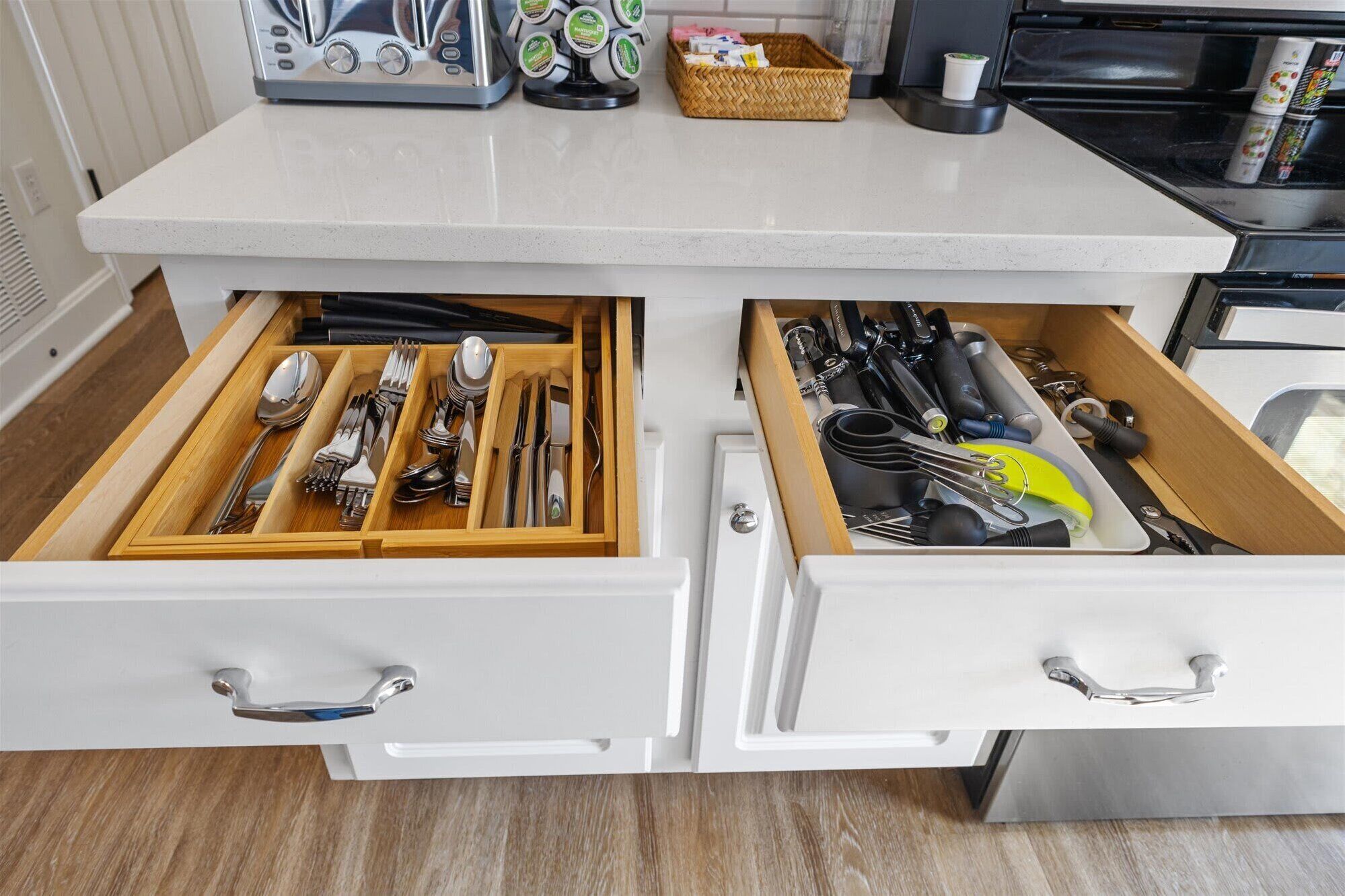 A kitchen drawer with utensils and a toaster on the countertop.