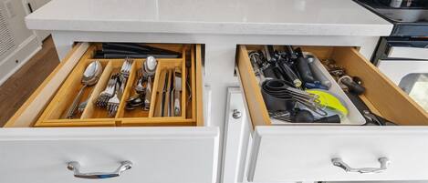 A kitchen drawer with utensils and a toaster on the countertop.
