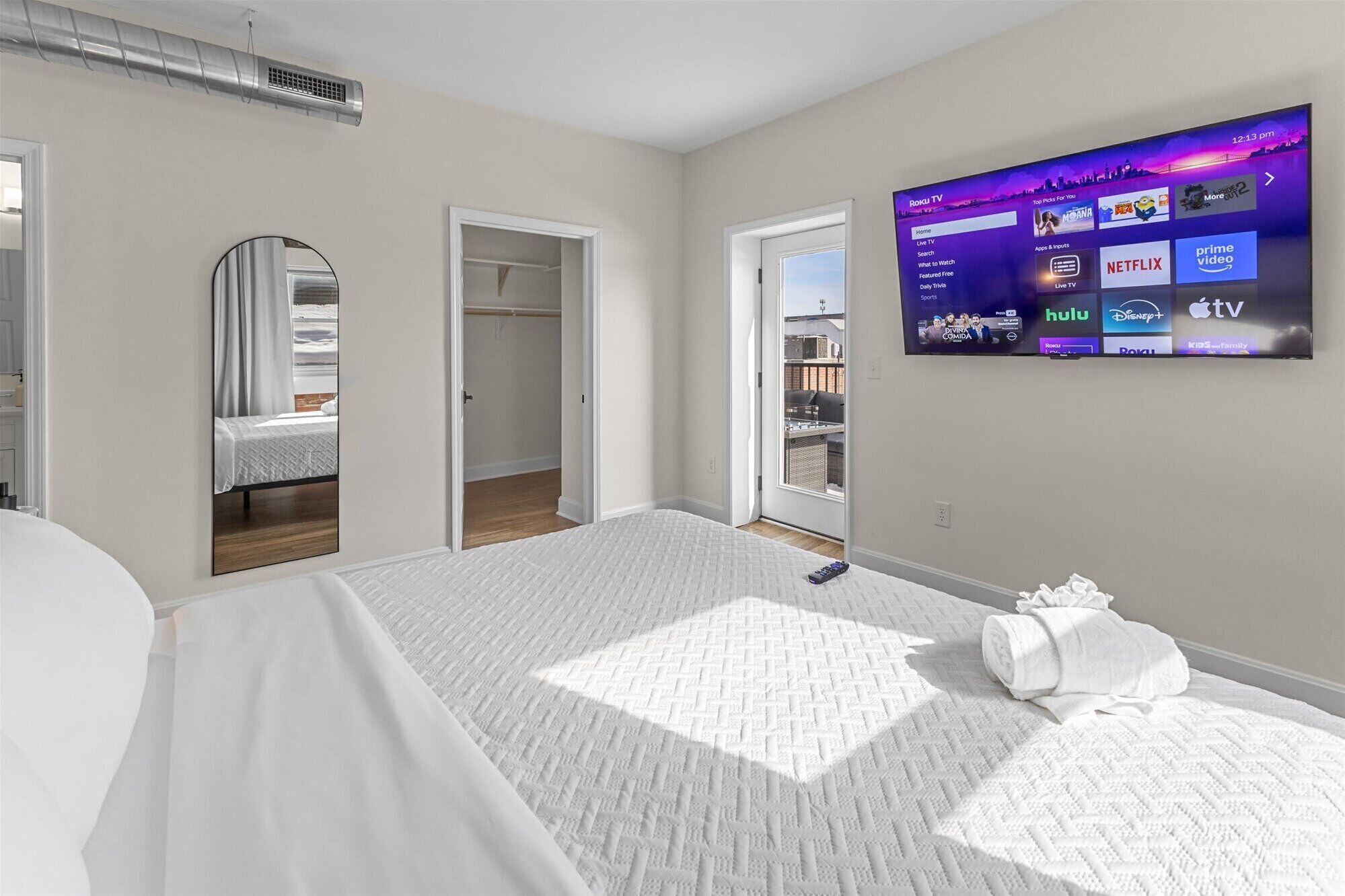 Habitación de hotel con cama, televisor mostrando servicios de streaming y vistas al exterior.
