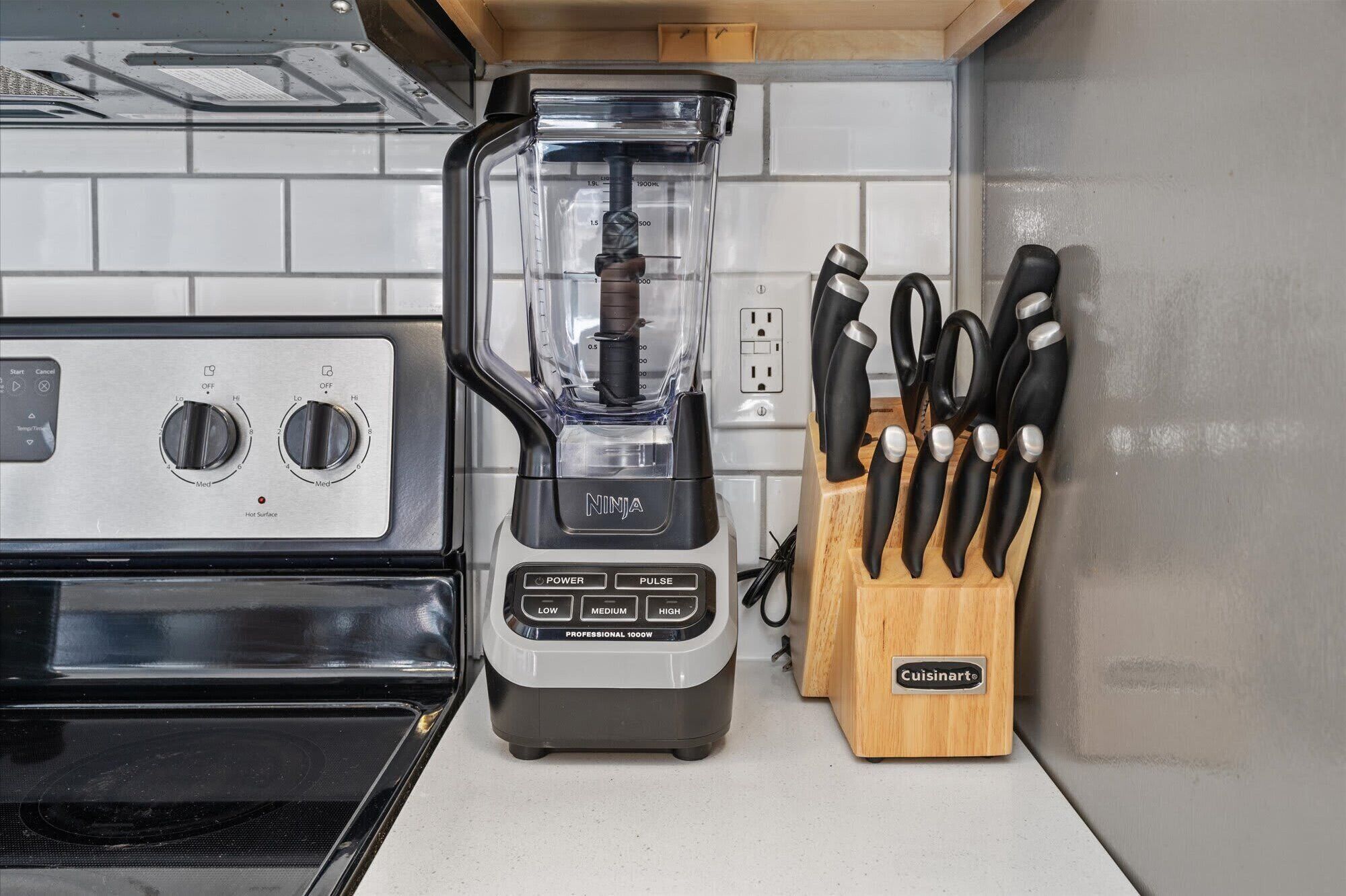A kitchen with a blender, a stove, and a knife block.