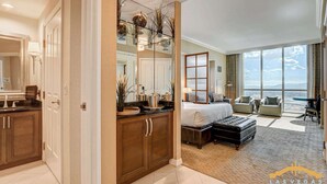 A spacious bedroom with a large bed, a sitting area with a view, and a bathroom with a mirror and sink. - MGM Signature-31-816 Jacuzzi Studio (Las Vegas)
