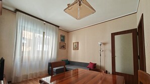 A dining area with a wooden table and chairs, a sofa, and a lamp.