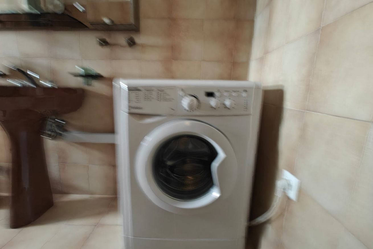 En tvättmaskin med frontmatning i ett badrum med handfat och kaklade väggar.