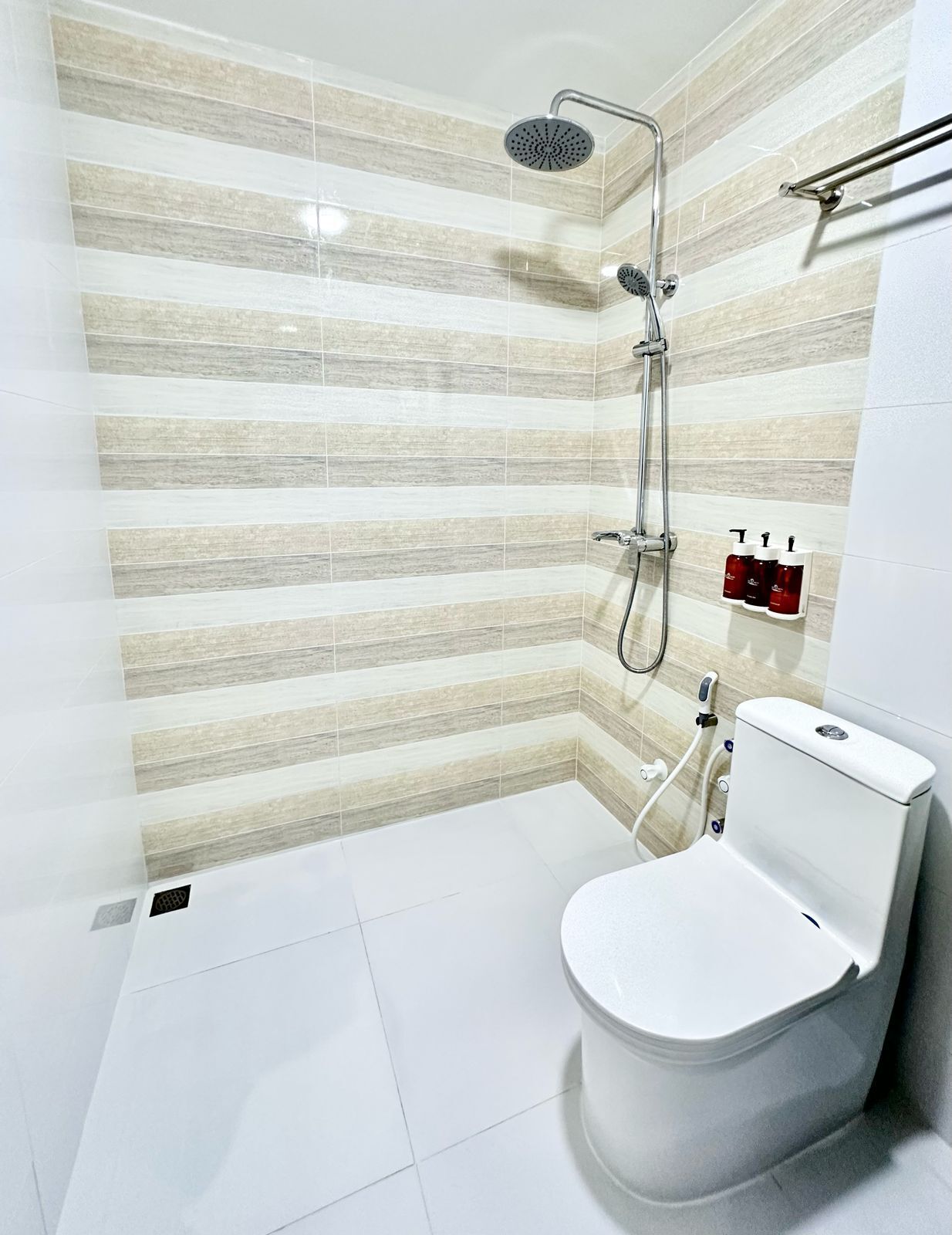 A modern bathroom with a shower, toilet, and towel rack.