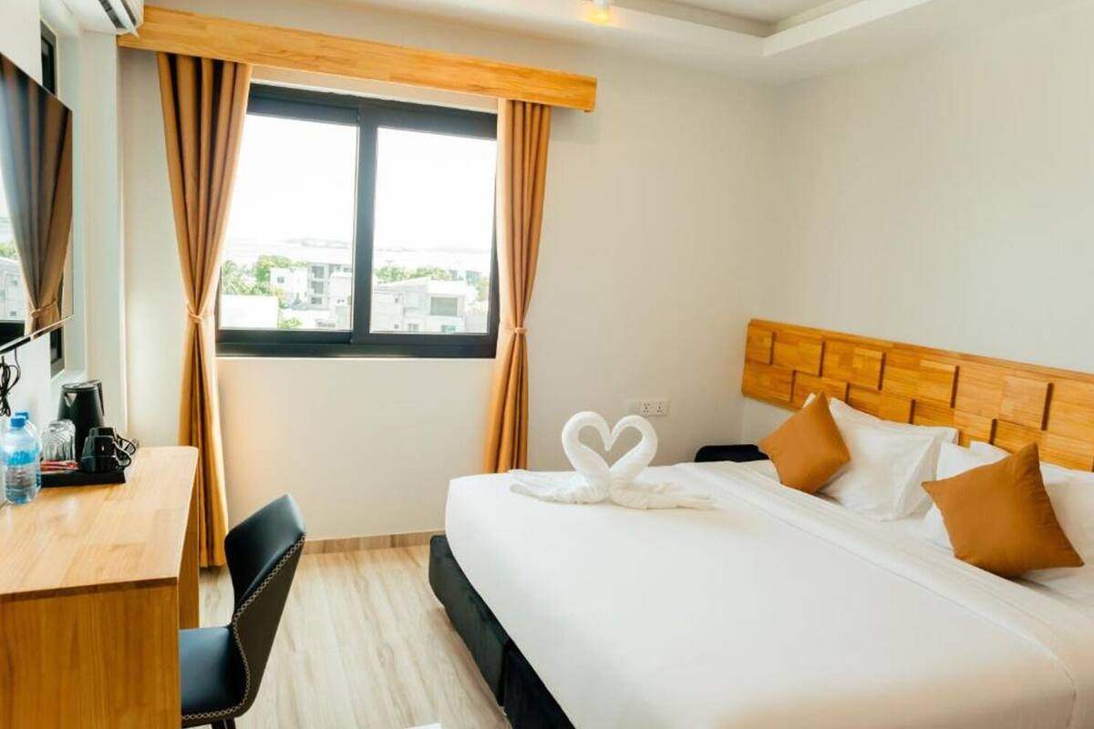 A hotel room with a bed, a desk, and a chair.