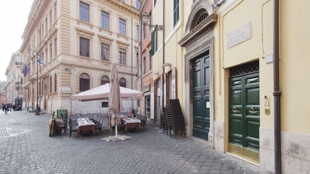 Una calle adoquinada con mesas al aire libre y un edificio con una puerta verde.