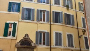 Un edificio amarillo con múltiples ventanas, algunas con persianas.