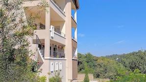 A multi-story building with balconies, surrounded by lush greenery and a clear blue sky. - Hillsgate EXPERIENCE  (Nairobi)