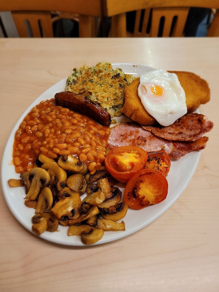 A plate of food including beans, mushrooms, tomatoes, sausages, eggs, and toast.