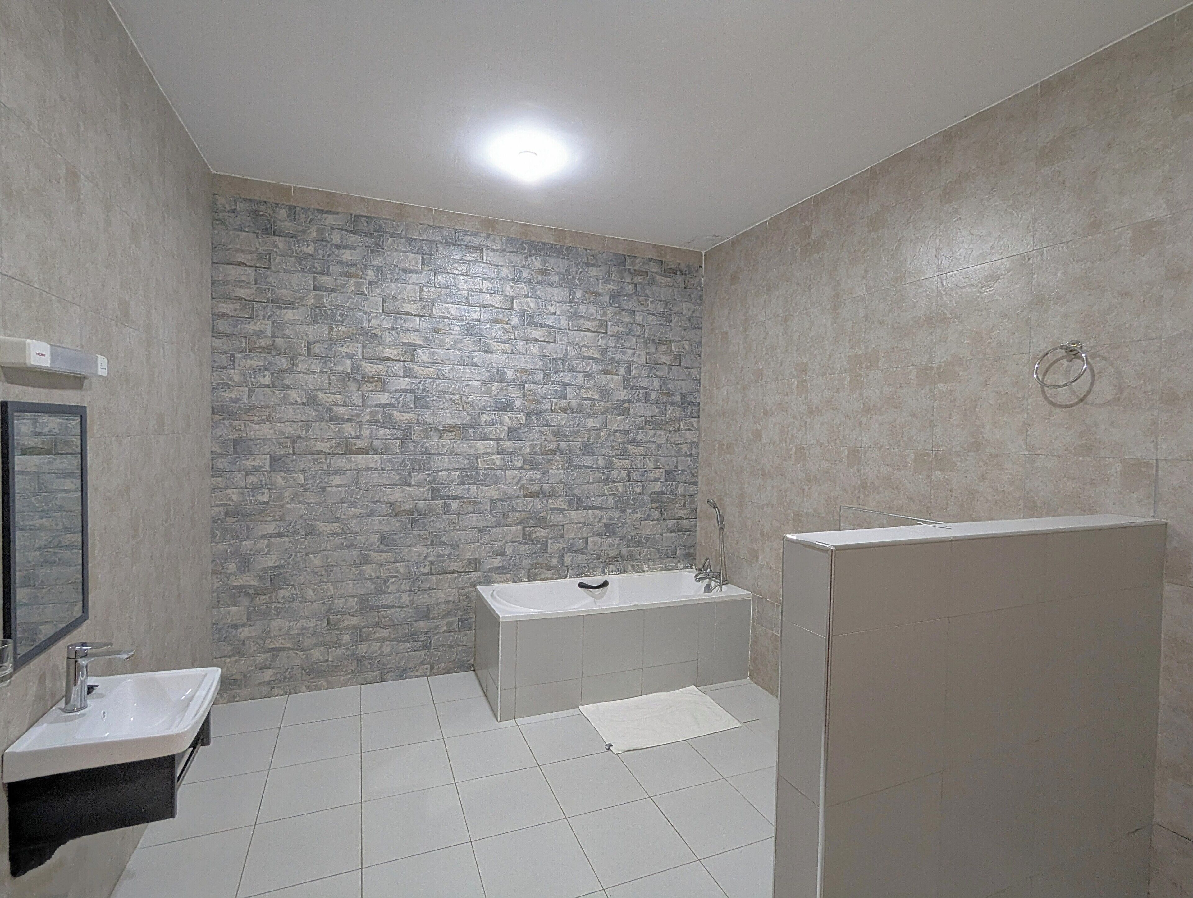 A bathroom with a stone wall, a bathtub, a sink, and a shower area.