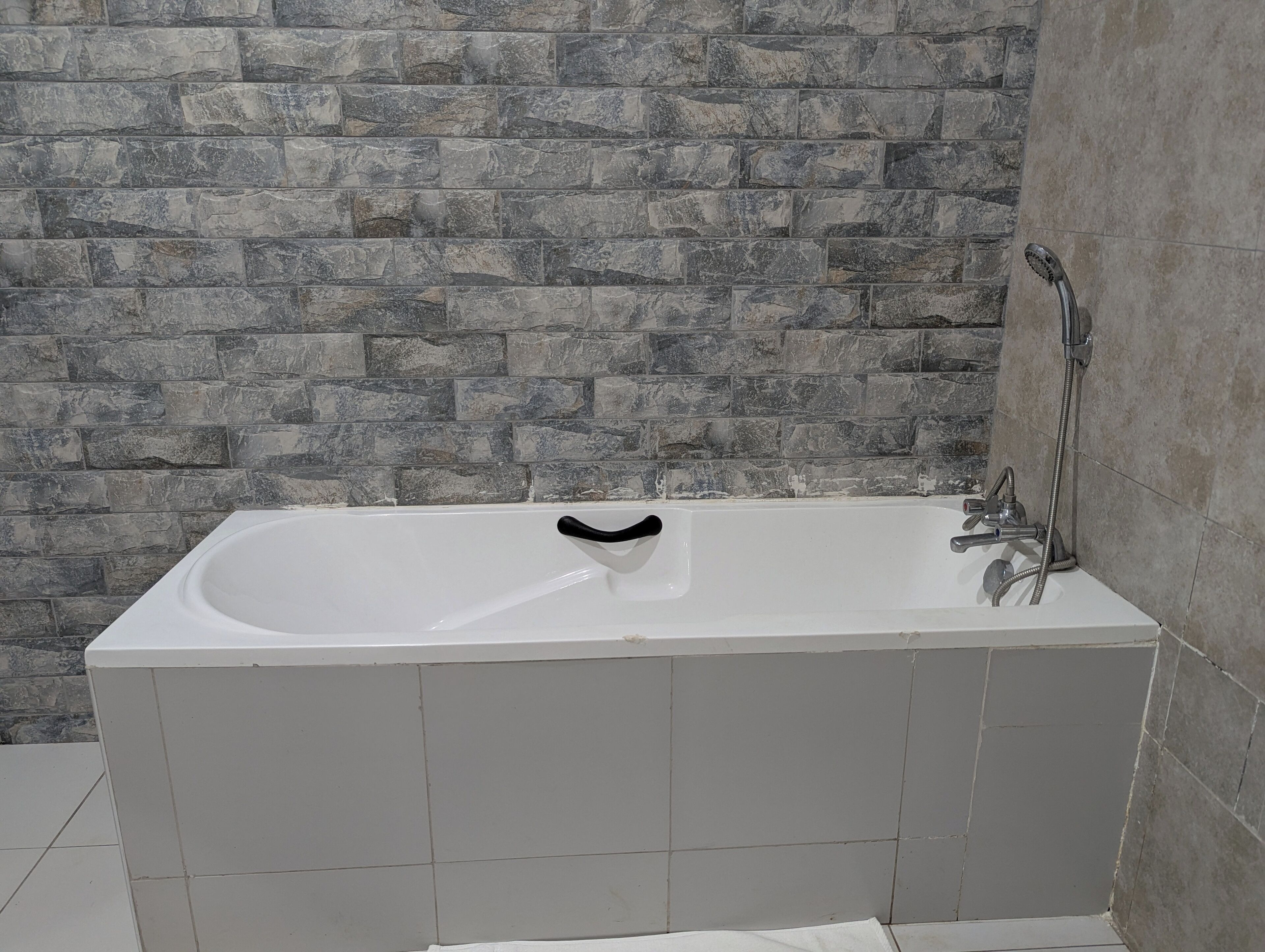 A white bathtub with a black soap dish, a showerhead, and a handheld shower attachment.