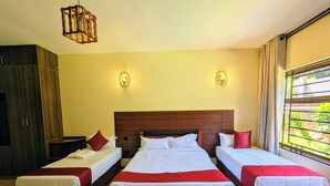 A hotel room with three beds arranged in a row, a wooden headboard, two wall sconces, and a large window with curtains. - Hillsgate EXPERIENCE  (Nairobi)