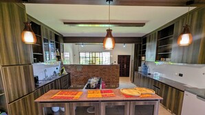 A modern kitchen with wooden cabinets, a central island with a built-in sink, and pendant lighting. - Hillsgate EXPERIENCE  (Nairobi)
