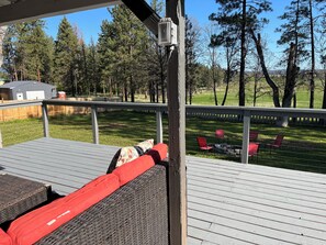 Une terrasse couverte, aménagée avec du mobilier d’extérieur, et offrant une vue sur une cour verdoyante avec des arbres.