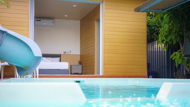 A modern hotel room with a large window, a bed, and a small bedside table. - Cozy gray garden (Pattaya)