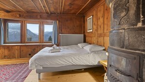 Una habitación de madera con una cama, un radiador y un horno de piedra.