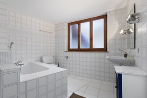 Een badkamer met een bad, toilet en wastafel.