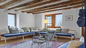 Una habitación con un techo grande de madera, un conjunto de sofá azul, una mesita y una alfombra estampada.