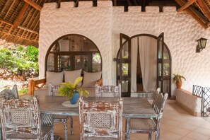 Un espace de restauration extérieur rustique, agrémenté d’un mur en pierre, de mobilier en bois et offrant une vue sur le jardin.
