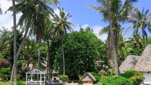 Un resort tropical con piscina, palmeras y cabañas de techo de paja.