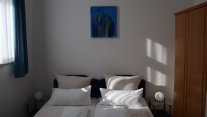 Une chambre d’hôtel avec deux lits, un tableau au mur et une armoire.