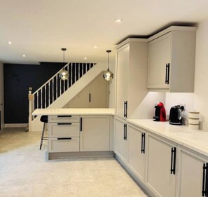 Enjoy cooking in this well-equipped kitchen with a central island, stainless steel sink, and white cabinets.