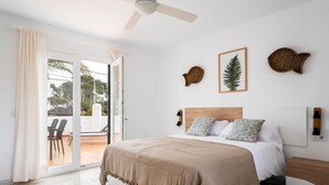 A bedroom with a bed, a ceiling fan, a sliding glass door to a patio, and wall decor. - APARTAMENTO FONA (Cala Blanca)