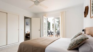 A bedroom with a bed, a ceiling fan, and a view of an outdoor area with a table and chairs. - APARTAMENTO FONA (Cala Blanca)