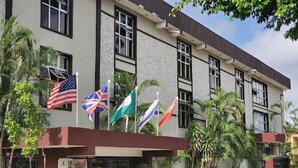 A building with multiple flags, including the American and British flags, and several palm trees. - Davies Hotels  (Ibadan)