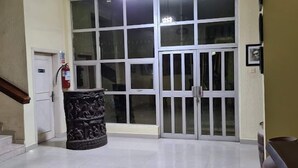 A hallway with a staircase, a fire extinguisher, a decorative pillar, and a set of double doors. - Davies Hotels  (Ibadan)