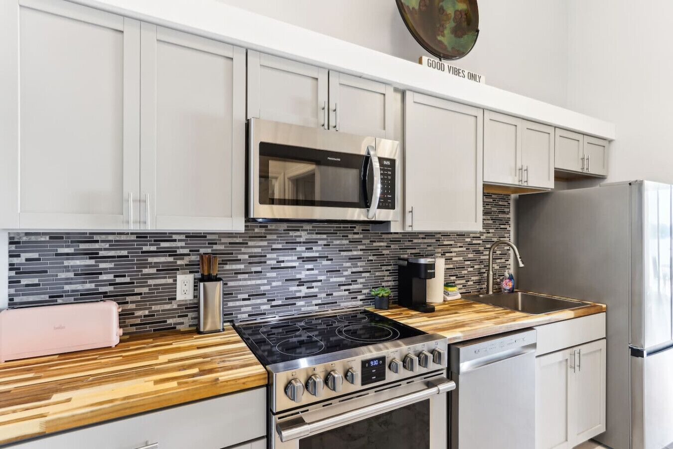 A modern kitchen with white cabinets, a stainless steel microwave, a gas stove, and a built-in dishwasher.