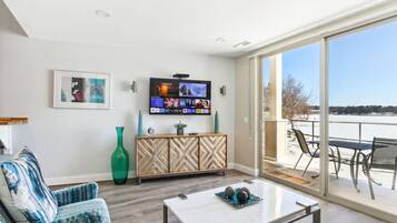 Una sala de estar con un televisor grande, un sofá, una mesa de centro y vistas a un paisaje nevado a través de un ventanal corredero.