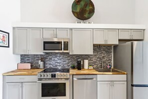 Una cocina moderna con electrodomésticos de acero inoxidable, salpicadero de azulejos y armarios de tonos claros.