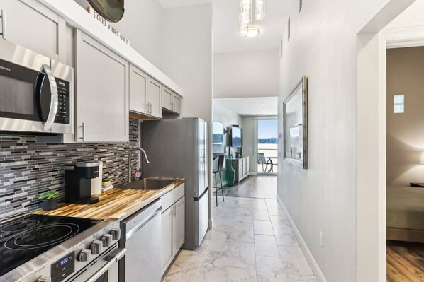 A modern kitchen with a stainless steel range, a coffee maker, and a microwave. - Luxury Beachfront Retreat at Delton Grand (Wisconsin Dells)