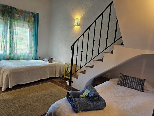 Un dormitorio con dos camas, una escalera y una mesita de noche con lámpara.