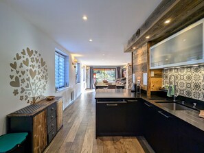 A modern kitchen with a central island, wooden cabinetry, and a stone accent wall.