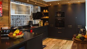 Une cuisine moderne avec des meubles de couleur sombre, un plafond en bois et un revêtement mural décoratif.