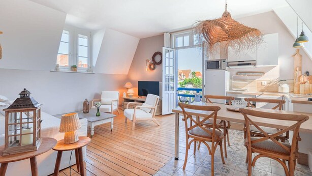 A spacious loft apartment with a high ceiling, a large open kitchen, and a dining area with wooden furniture.